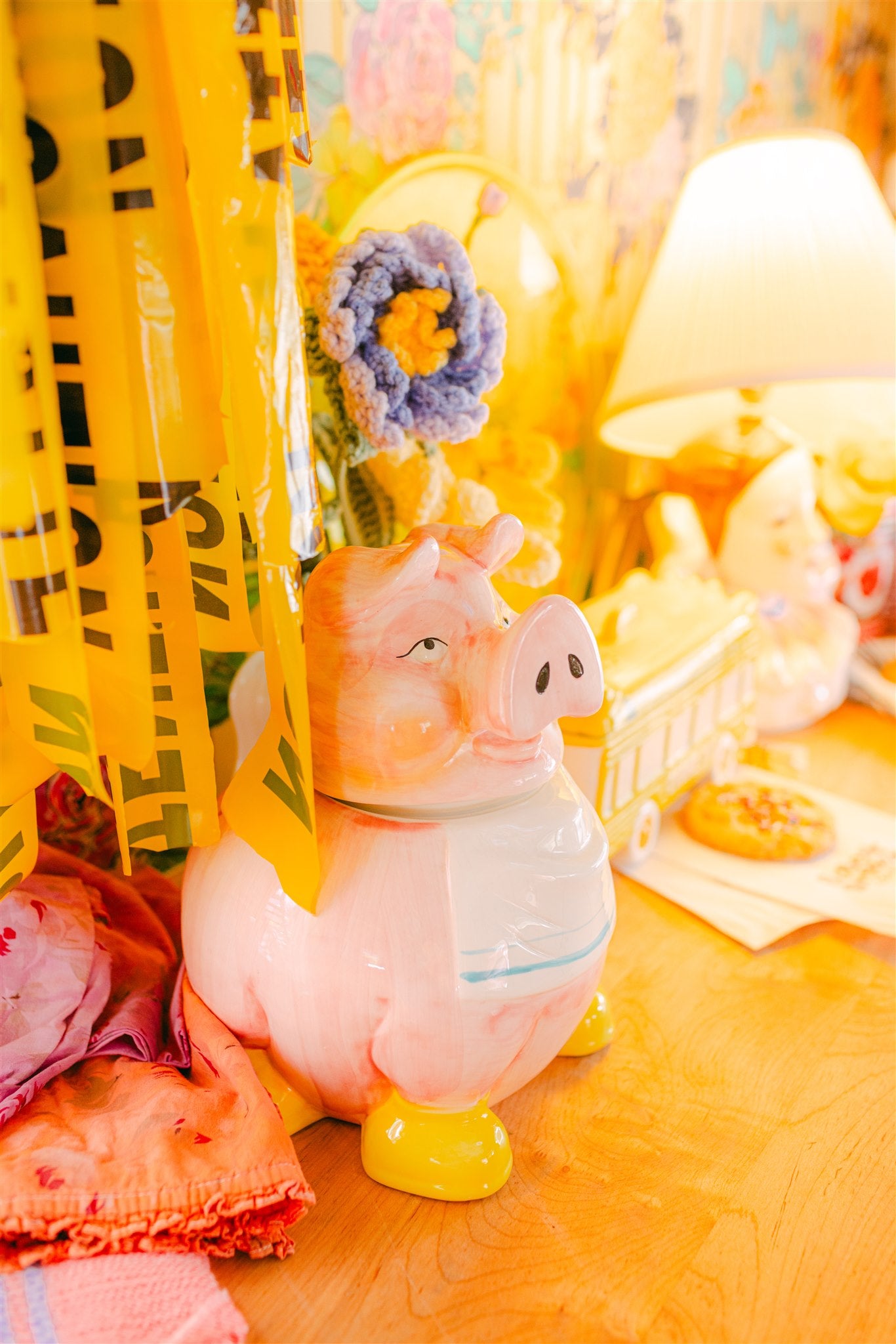 Pink piggy bank on a wooden surface with colorful curtains in the background
