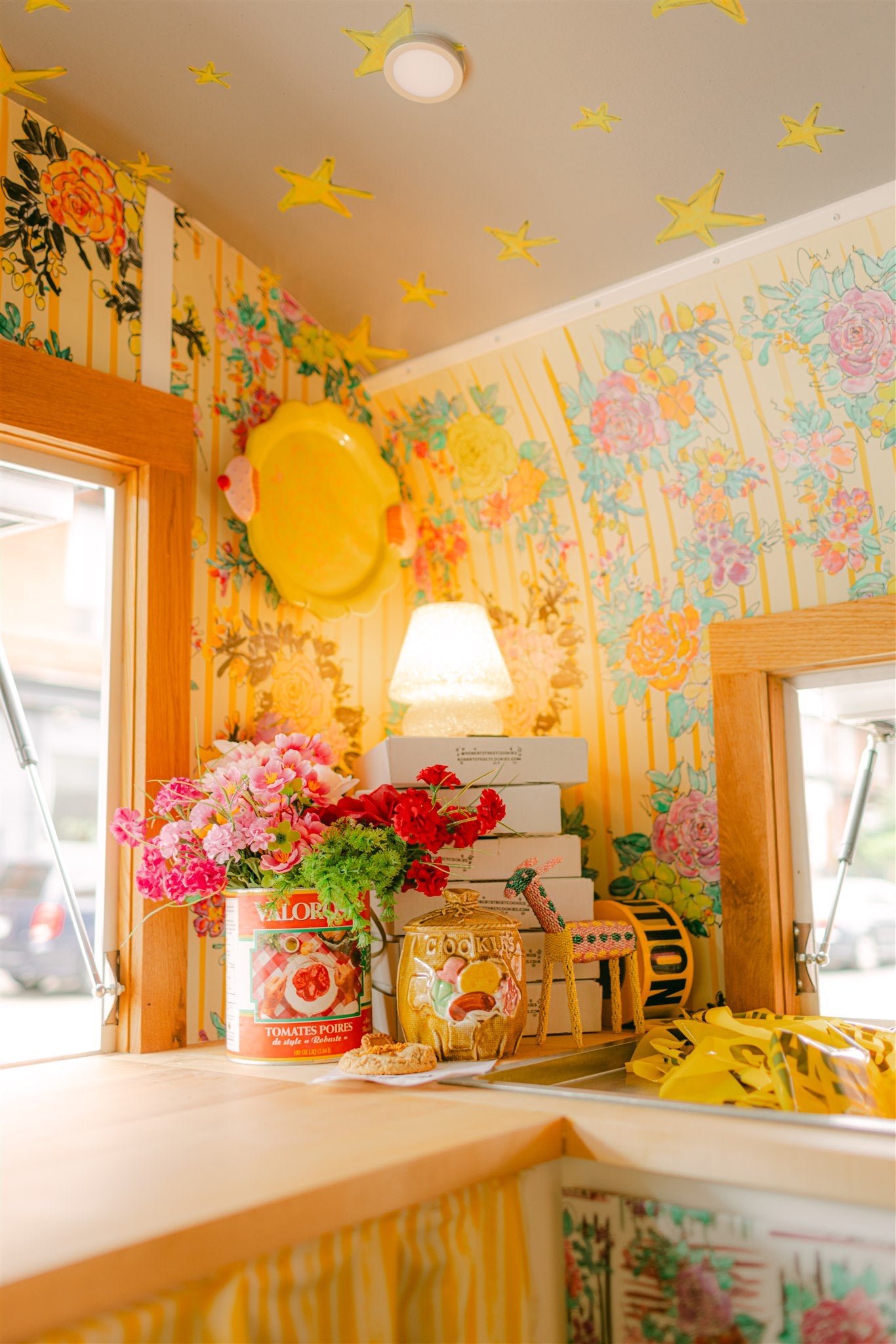 Colorful interior with floral wallpaper, decorative items, and a lamp.