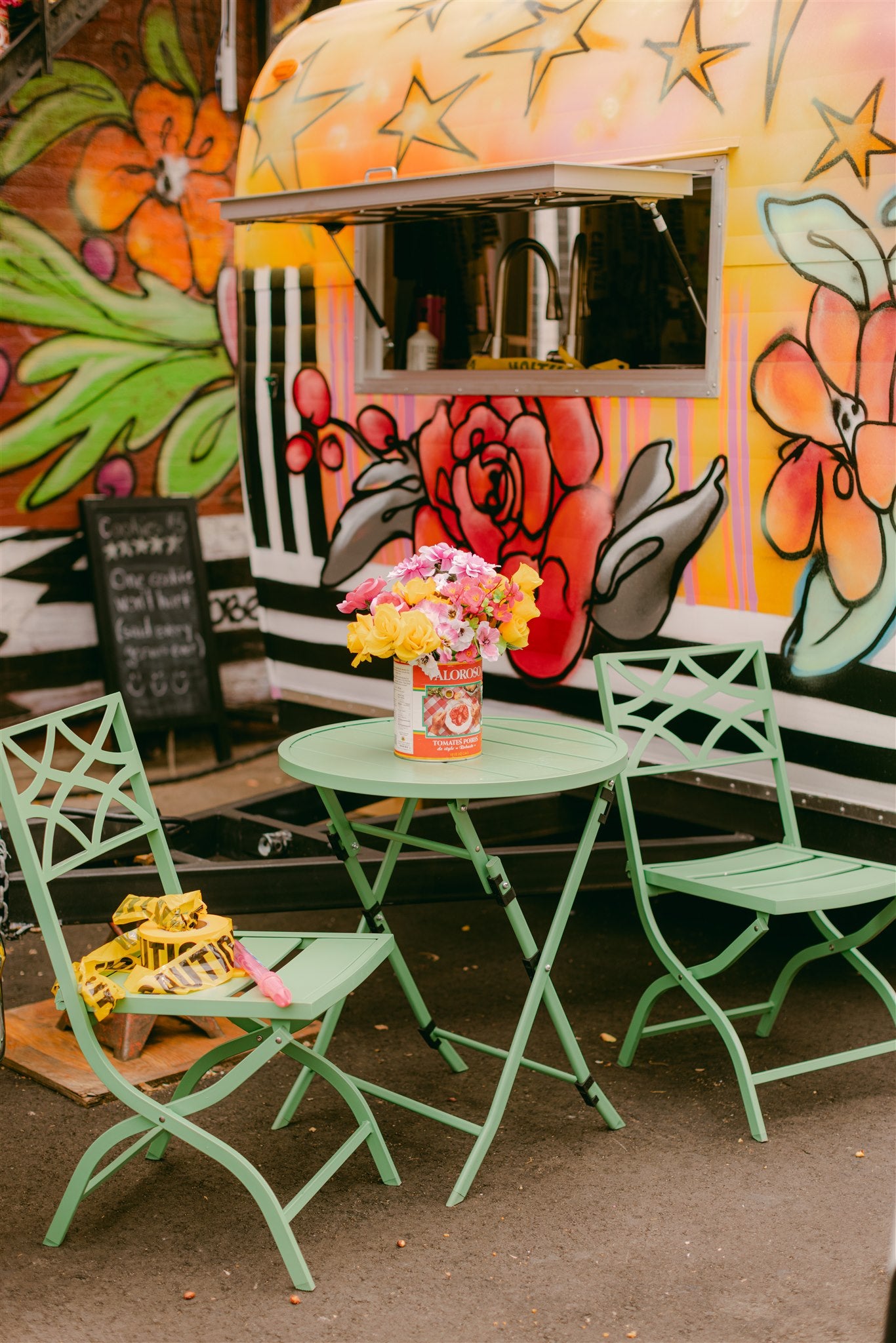 Green metal chairs and table set against a colorful mural background