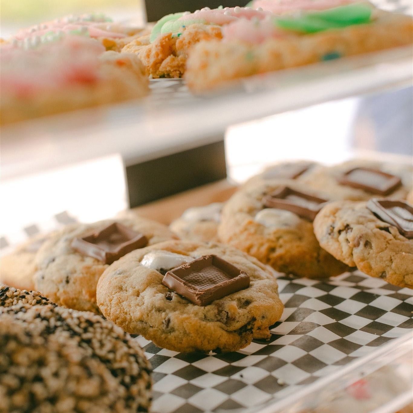 Assorted cookies on a checkered surface with a blurred background of more cookies.